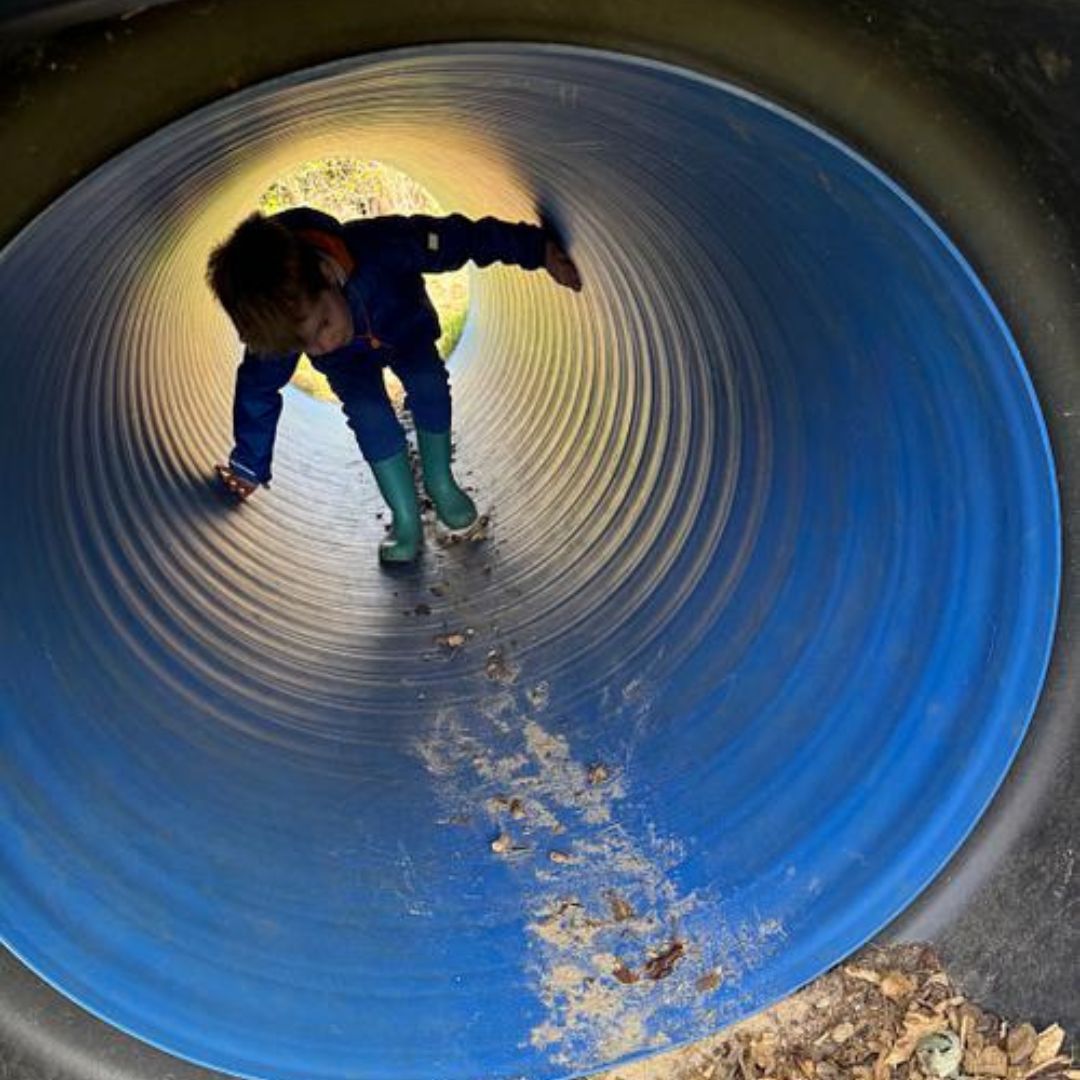 A child playing in a large blue tunnel on a trip to Flore farm
